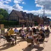 Outdoor cafe with patrons seated Stratford upon Avon under a sunny sky.
