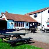 The Yorkshire House pub with outdoor seating and blue sky backdrop.