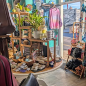 Shop interior with merchandise, plants, and a table near the entrance.