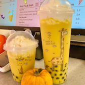 Two yellow drinks with giraffe design, Have a Nice Day sign and pumpkin.