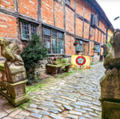 Historic building exterior with stone gargoyles, text, and cobblestone path.