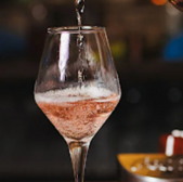 Pouring pink champagne into a wine glass, a festive celebratory moment in detail.