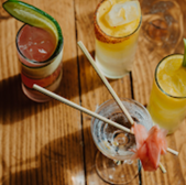 Colorful cocktails on wooden table with cucumber garnish and chopsticks