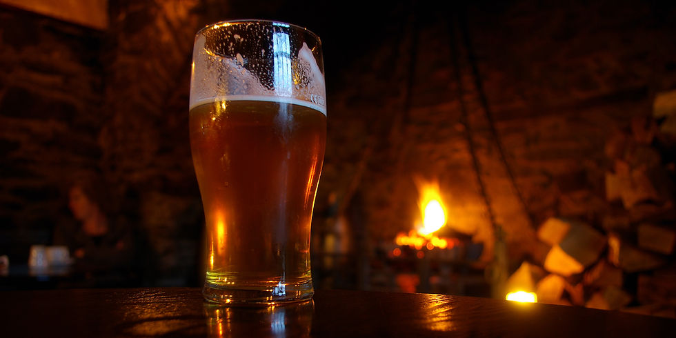 Glass of beer in front of a fireplace with burning fire.