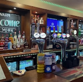 The York pub bar with taps, and bottles, and the sign saying Welcome.