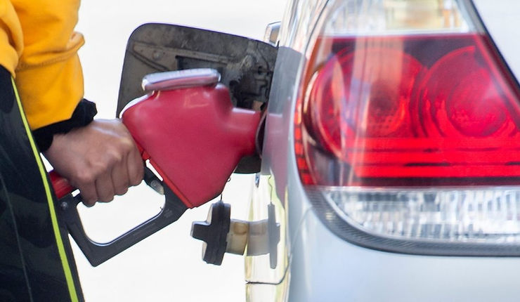 Conductor llenando el tanque de su automóvil en una estación de servicio.