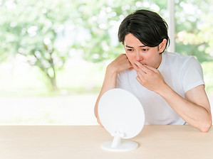鏡を見て鼻の頭を気にする男性