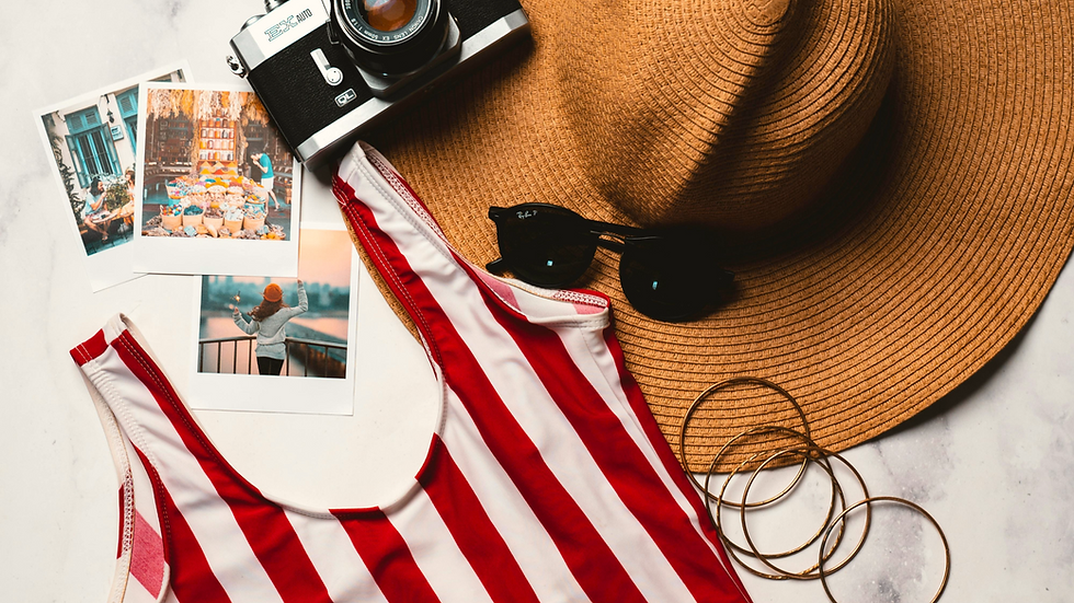 Camera, hat, sunglasses, red-striped swimsuit, and photos on marble surface. Vibrant travel mood with hints of adventure.