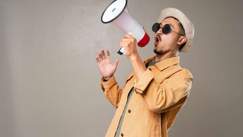 Man Wearing Orange Jacket While Yelling on a Megaphone