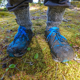 Muddy trail-running shoes meeting the mossy forest ground