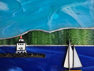 A stained glass piece in greens and blues depicting a landscape, a lighthouse and a sailboat.