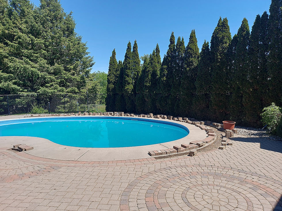 A swimming pool surrounded by interlock, some of it loose and waiting to be placed.