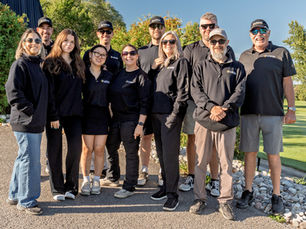 A group of people, the Lagois team, standing in the sunshine on a golf course.