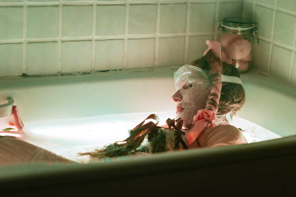 a woman in a green bathtub with a face mask and wireless curlers to promote the show you're needy (sounds frustrating) at edinburgh fringe 2024