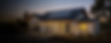Modern home with solar panels and a backup battery system at dusk.