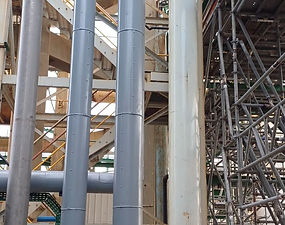 Tuyauterie industrielle grise et échafaudages complexes.