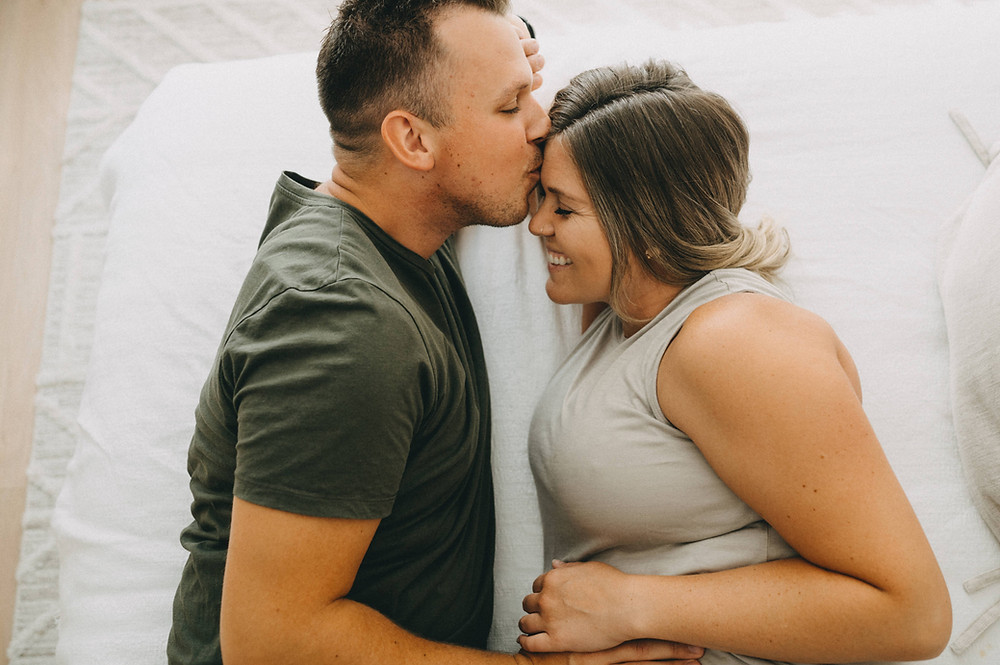 Dad and pregnant mom lying in bed smiling