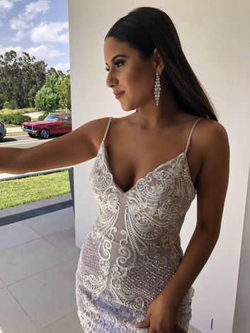 Young woman in a white dress, posing outdoors near a forest.
