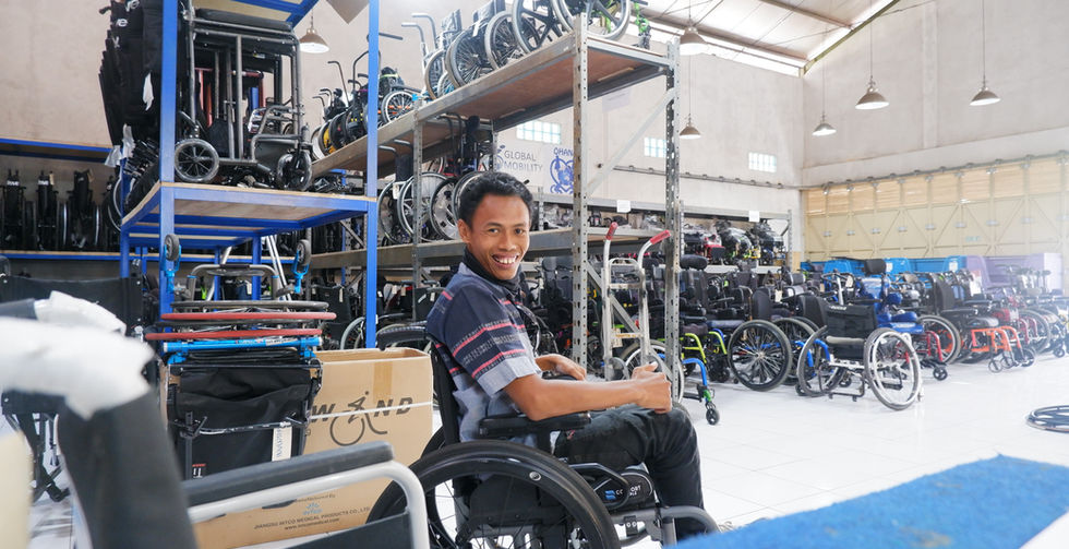 Man smiles in wheelchair surrounded by multiple wheelchairs at Our Facility.