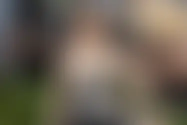 Anne Hathaway smiles on the 2026 Met Gala red carpet wearing an elegant black strapless gown with artistic white detailing, paired with sparkling diamond jewelry and a sleek bun hairstyle.