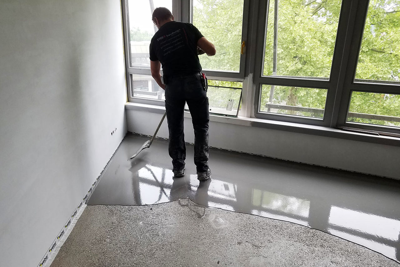 Die Profis von STERK estrich ebnen die eingebrachte Masse und kontrollieren zeitgleich die Einbauhöhe.