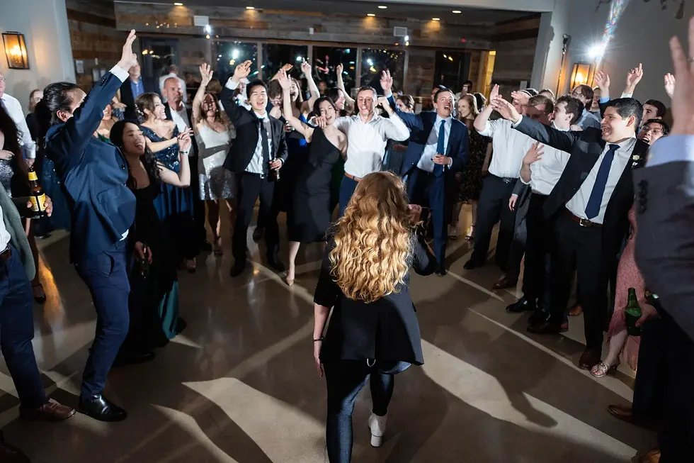 Multi-generational wedding guests of all ages dancing with hands raised during bouquet toss celebration in modern Austin