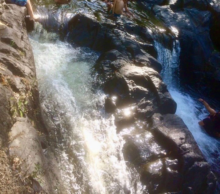 Ein atemberaubender Badeplatz im Regenwald mit einer natürlichen Wasserrutsche aus Felsen. Das kristallklare Wasser fließt sanft durch die üppige Vegetation und lädt zu einem erfrischenden Naturerlebnis ein.
