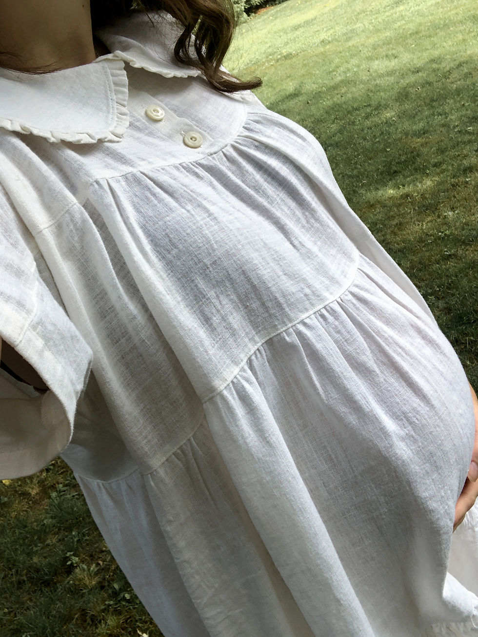 A woman wearing a handmade white tiered maxi dress