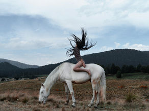 Woman on a white horse flipping her hair