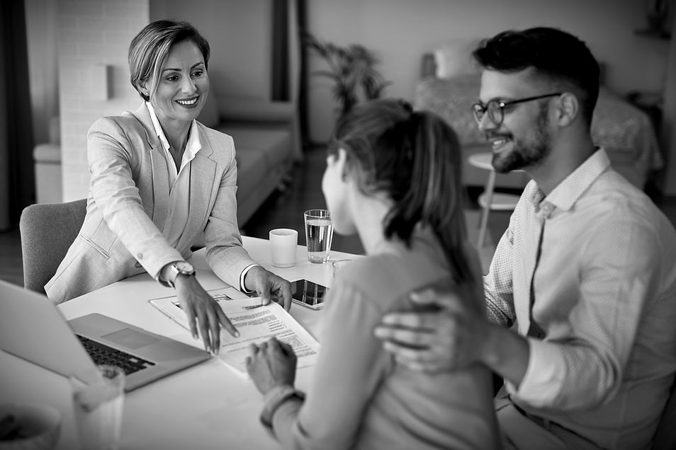 happy-real-estate-agent-having-meeting-with-young-couple-pointing-place-signature-their-co
