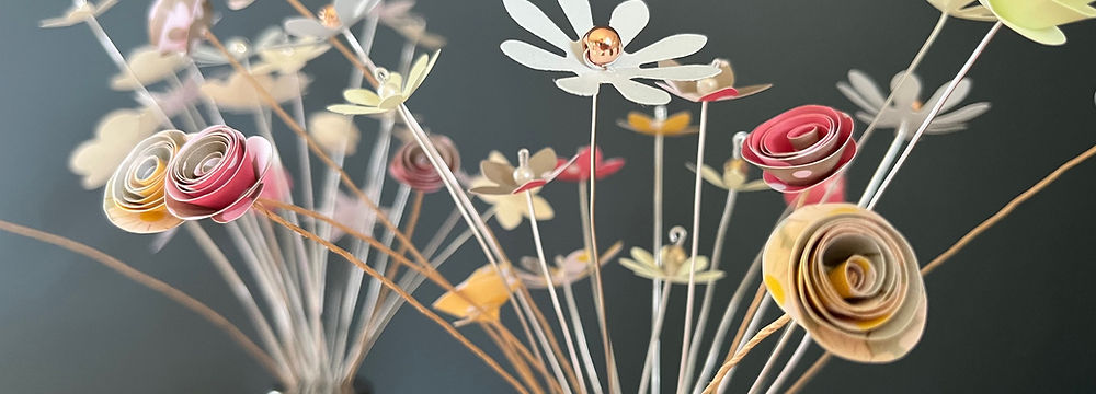Small colourful flowers made of card and displayed in glass 'shakers'