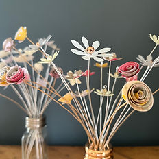 Small colourful flowers made of card and displayed in glass 'shakers'