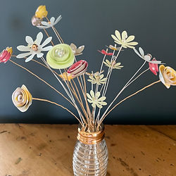 Small colourful flowers made of card and displayed in a glass 'shaker'
