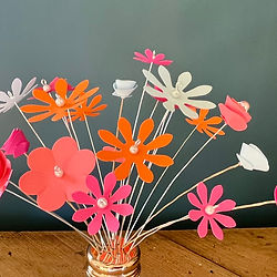 Small brightly coloured flowers made of card and displayed in a glass 'shaker'