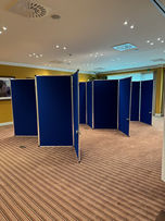 A flexible event space with blue posterboards arranged in a zigzag pattern. The room has a striped carpet, recessed lighting, and a framed picture on the wall. The setup showcases Aventix's practical and versatile conference solutions.
Tags:
Event Space
Posterboards
Posterpanels
Flexible Setup
Aventix Services
Temporary Booths
Striped Carpet
Recessed Lighting
Versatile Venue
Indoor Event
Technical Equipment