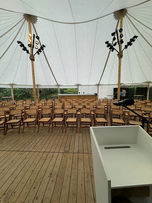 ndoor event setup under a large white tent with rows of wooden chairs facing a podium with a microphone. Wooden plank floor and poles with stage lights. A person stands near the edge of the tent, with greenery visible outside. Ideal for a speech or presentation.
Tags:
Event Tent
Wooden Chairs
Podium with Microphone
Stage Lights
Wooden Plank Floor
Outdoor Setup
Speech Venue
Presentation Setup
Event Planning