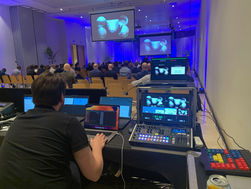 Professional conference setup with a person operating audiovisual equipment in the foreground. The audience faces a stage with two large screens displaying the same image. Blue lighting and plants create a professional ambiance.
Tags:
Audiovisual Setup
Professional Conference
Aventix Services
Event Management
Blue Lighting
Technical Support
Audience Engagement
Stage Presentation
Event Equipment