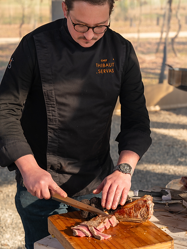 Chef Thibaut Servas en train de trancher une pièce de viande juteuse, mettant en valeur son savoir-faire culinaire et l'attention portée aux détails dans chaque plat.