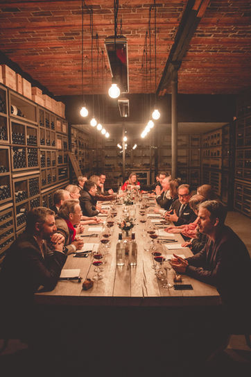 Dîner privé en cave à vins à Bordeaux organisé par le chef Thibaut Servas, avec des convives autour d'une grande table en bois