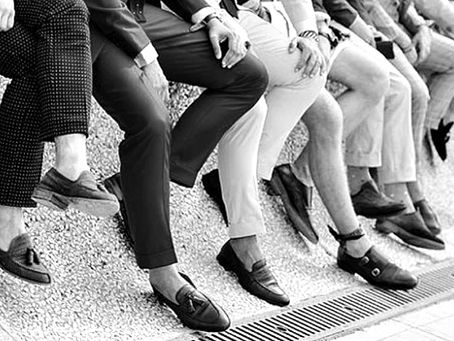 uomo elegante seduto con gambe accavallate calzini visibili abito formale stile maschile