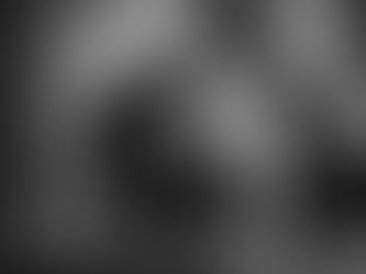 uomo in smoking che si sistema il papillon con profumo in primo piano bianco e nero