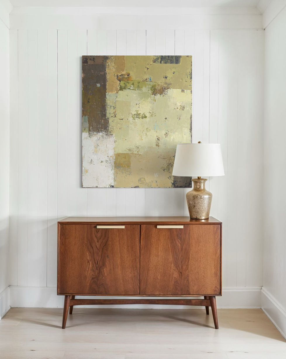 a table with a lamp and a painting on the wall above it