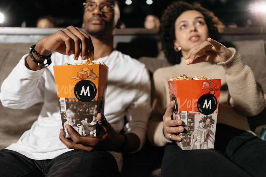 Couple sharing popcorn during a movie at a cinema