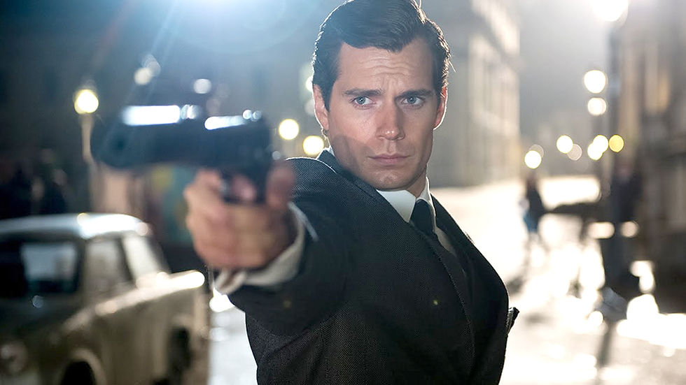 Suited man aims a handgun down a city street at night, lit by bright streetlights, with a tense, focused expression.