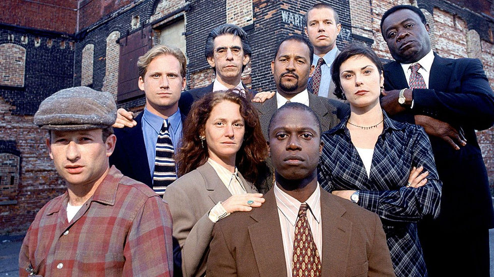 Seven serious professionals pose in front of a weathered brick building, like a cast photo in an urban alley.