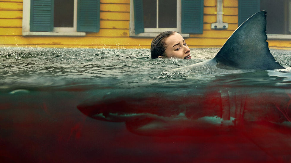 A woman in water near a shark fin looks anxious. A yellow house with blue shutters is in the background. The water is dark with a red hue.