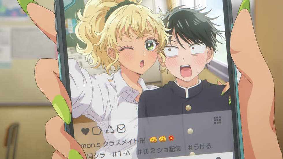 Handheld phone shows a blonde girl winking beside a shocked black-haired boy in school uniforms, with Japanese text on screen.