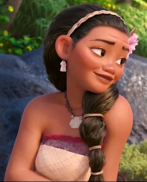 Smiling animated girl with braided hair and flower clip sits outdoors against rocks and greenery, looking to the side.