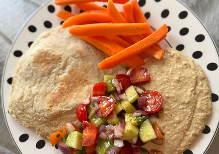 A bright, colorful Israeli vegetable salad, consisting of finely and uniformly diced red tomatoes, green cucumbers, and white or red onions. The salad is a vibrant mix of colors, possibly including yellow or orange bell peppers and green herbs like parsley or mint, and appears lightly dressed with oil and lemon juice.