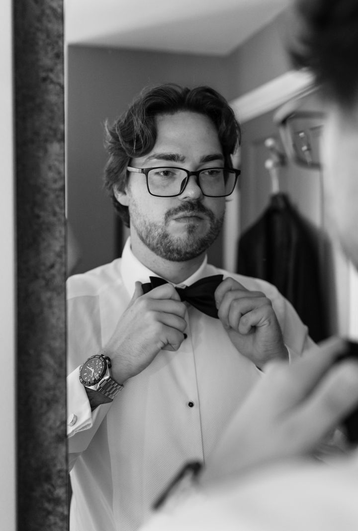 Groom adjusting bowtie in the mirror